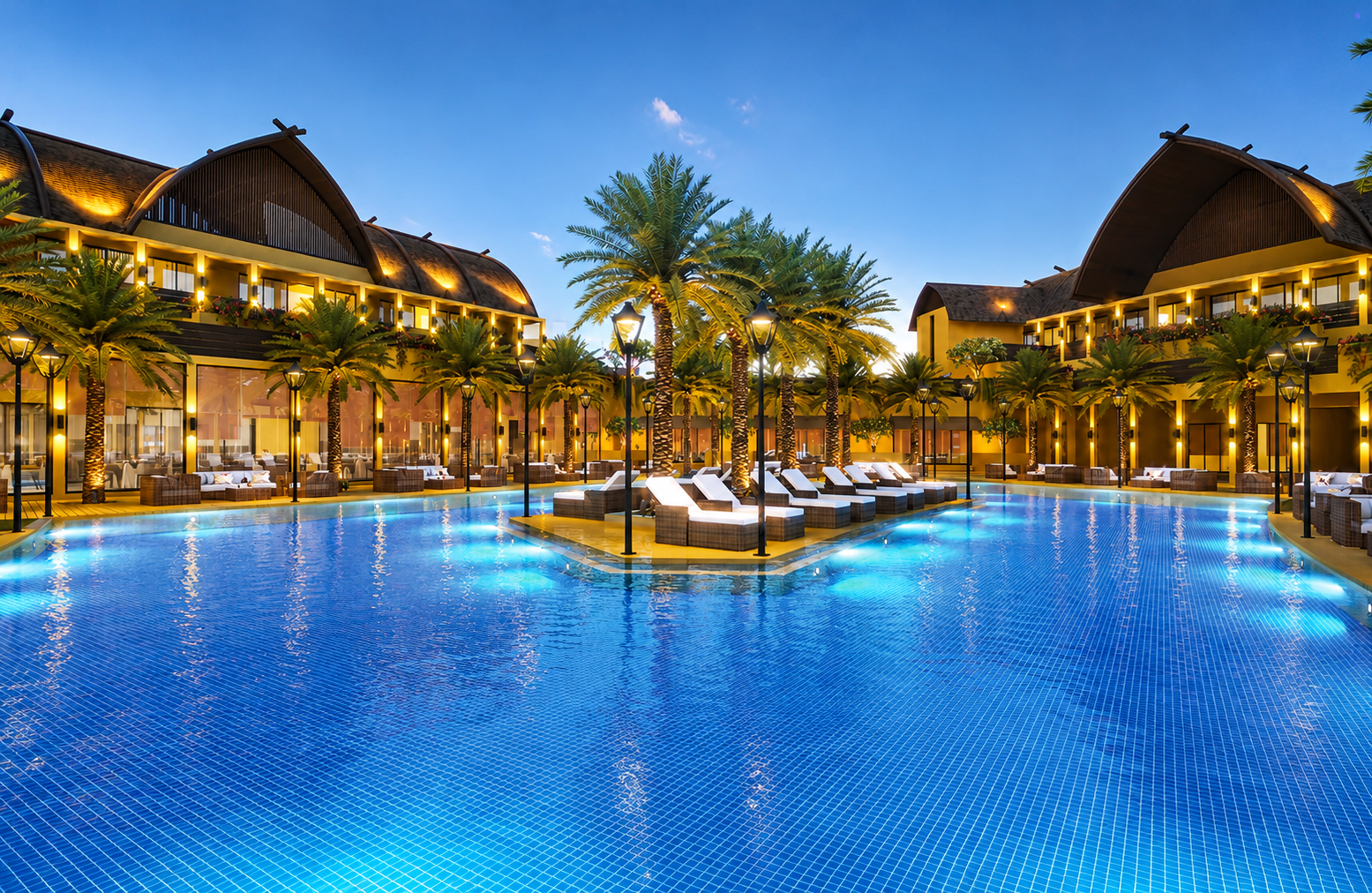 Club Laguna resort pool at dusk, framed by palms and warm-lit pavilions
